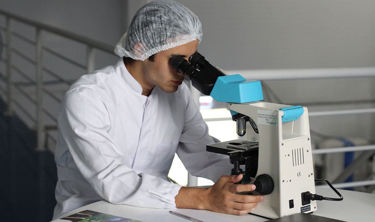 Healthcare work using microscope in lab.